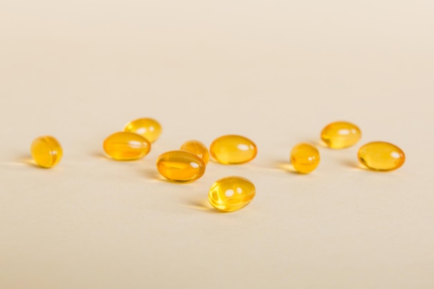 Photo tas de pilules jaunes sur fond coloré comprimés dispersés sur une table pile de capsule de gélatine molle rouge concept de vitamines et de compléments alimentaires