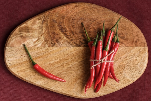 Un tas de piments rouges sur un support en bois sur fond noir. Concept culinaire. Épice chaude. Fermer.