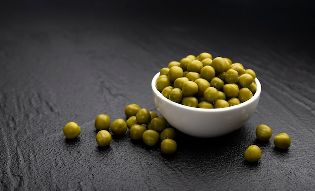 Tas de pois verts en conserve sur une surface noire