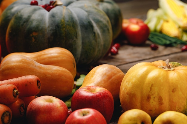 Tas de pommes rouges et de citrouilles sur une surface en bois