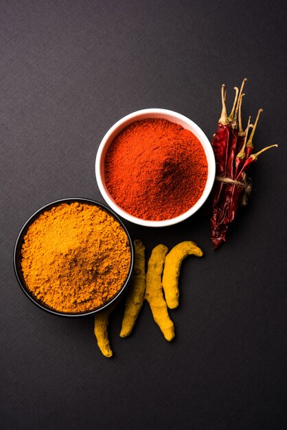 Tas de poudre de curcuma ou de haldi et de piment rouge ou de mirchi dans un bol en céramique sur une surface blanche ou noire