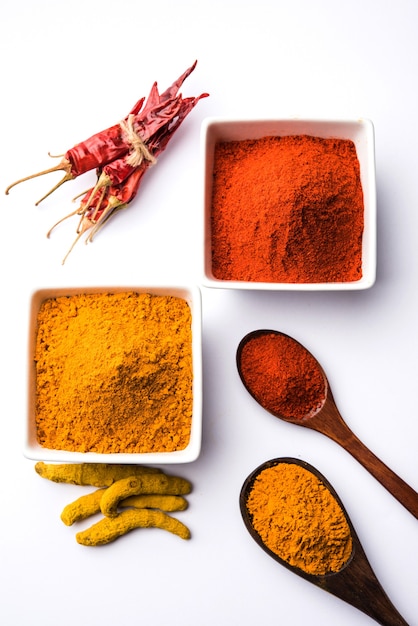 Tas De Poudre De Curcuma Ou De Haldi Et De Piment Rouge Ou De Mirchi Dans Un Bol En Céramique Sur Une Surface Blanche Ou Noire