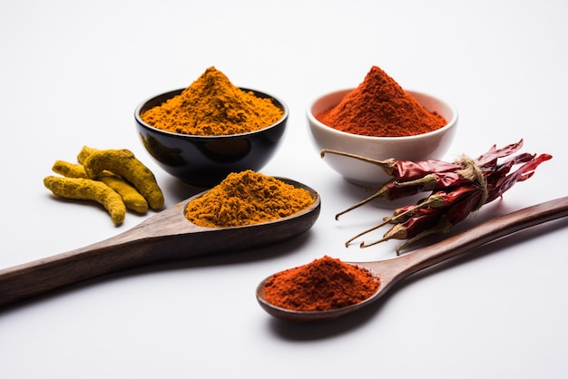 Tas de poudre de curcuma ou de haldi et de piment rouge ou de mirchi dans un bol en céramique sur une surface blanche ou noire