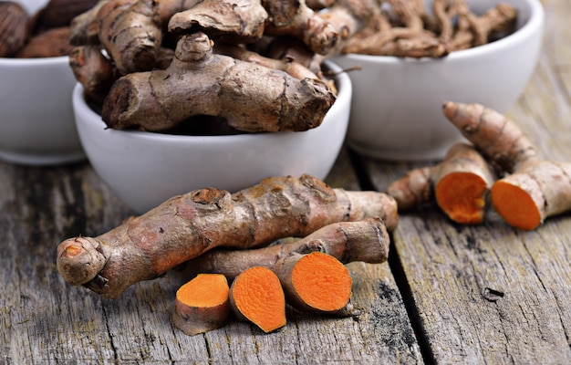 Tas de racines de curcuma fraîches sur table en bois