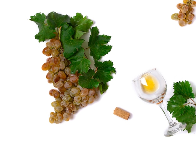 Un tas de raisins roses avec des feuilles avec un verre de vin sur un concept de vue de dessus de fond blanc