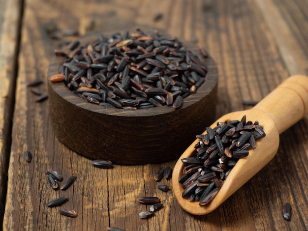 Tas de riz noir dans un bol en bois sur un gros plan de table en bois