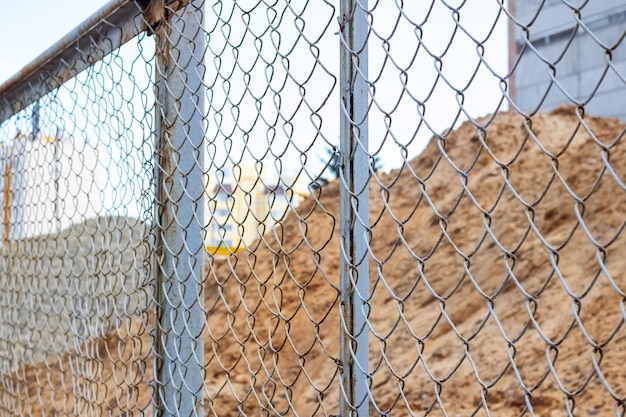 Tas de sable sur le chantier derrière une clôture métallique