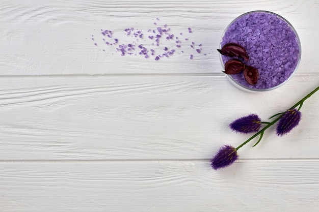 Tas de sel violet avec des fleurs sur une table en bois blanc