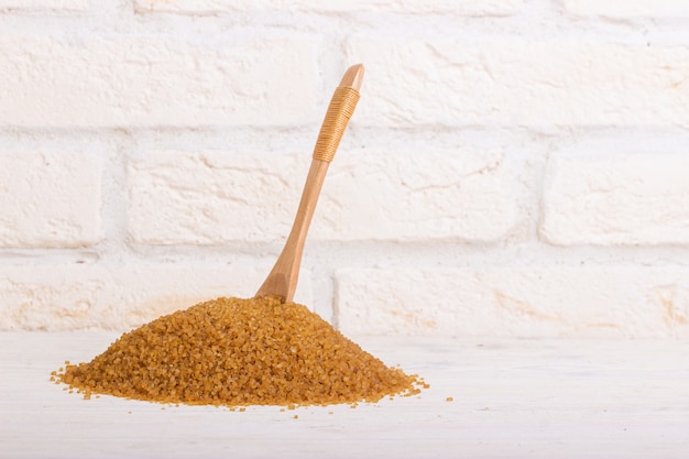 Un tas de sucre de canne avec une cuillère en bois coincée