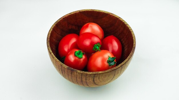 Photo tas de tomates dans un bol en bois tomates fraîches biologiques isolées sur blanc