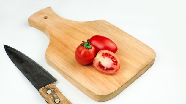 Photo tas de tomates sur une planche de bois, certaines tranchées avec un couteau tomates fraîches biologiques isolées sur blanc