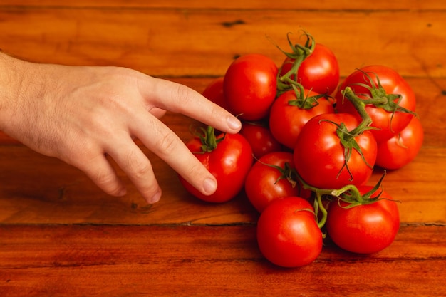 Tas de tomates sur table en bois main cueillette de tomates en tas de tomates fond en bois main