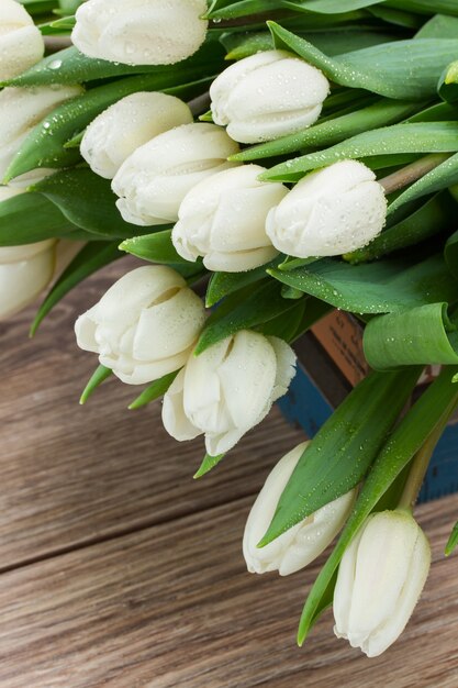 Tas de tulipes blanches fraîches sur table en bois