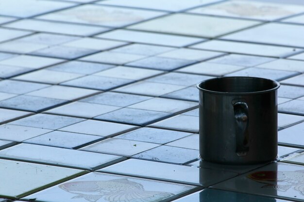 Tasse en acier inoxydable sur le plancher de carreaux.