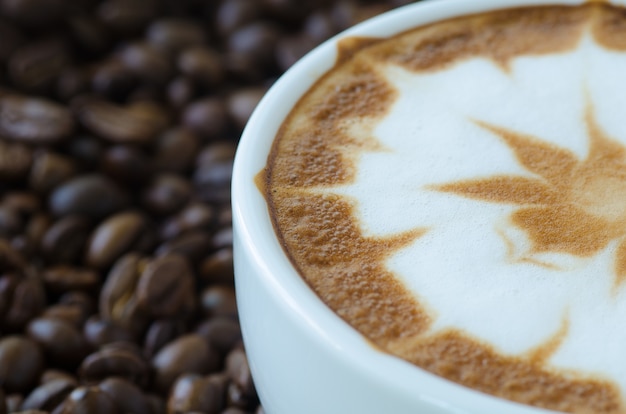 Une tasse d&#39;art latte sur fond de grain de café