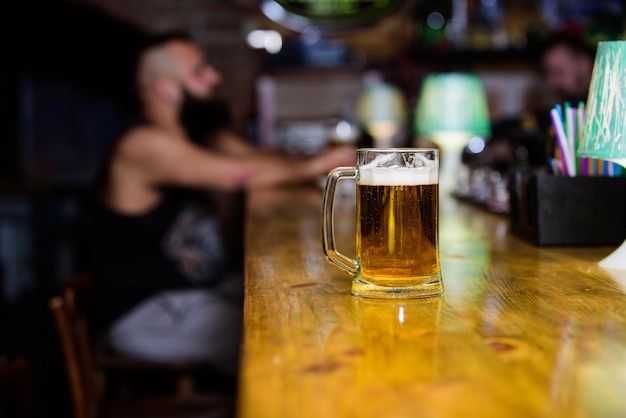 Tasse de bière sur le comptoir du bar fond défocalisé verre avec de la bière fraîche à mousse Tasse remplie de bière froide savoureuse dans le bar Vendredi tradition de loisirs concept de pub de bière style de vie de week-end