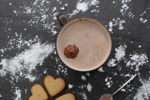 Photo une tasse de biscuits au cœur au chocolat chaud et une cuillère avec du cacao une nappe avec de la farine fête de noël