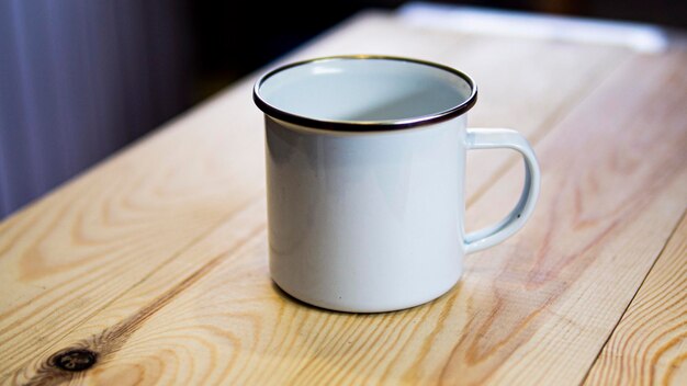 Une tasse blanche avec un bord marron est posée sur une table en bois.