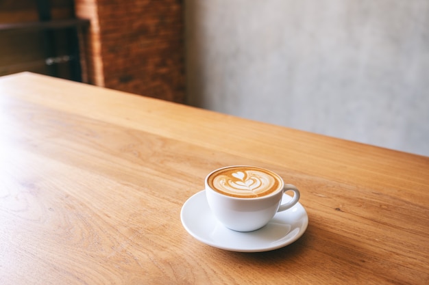 Une tasse blanche de café au lait chaud sur une table en bois