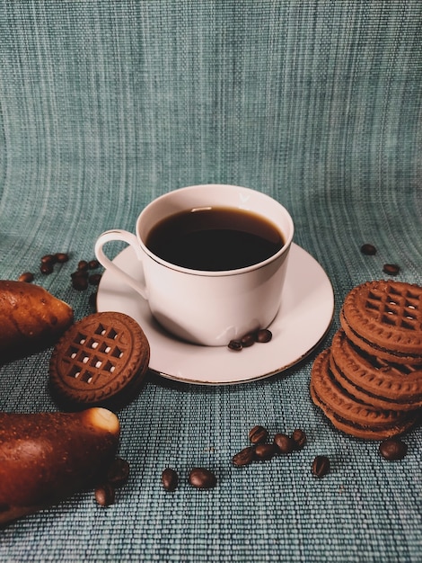 Tasse blanche de café et biscuits bruns ronds sur un fond bleu