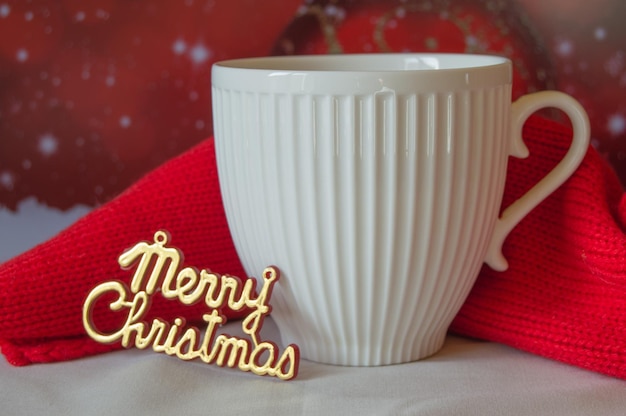 Tasse blanche de café et une écharpe rouge tricotée les mots Joyeux Noël