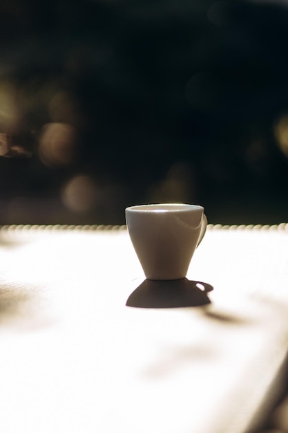 Tasse blanche de café expresso sur la table à l'ombre du soleil de la tasse