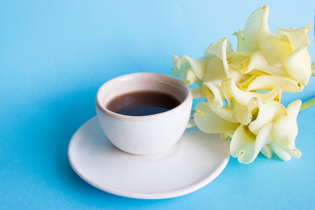 Photo tasse blanche de café sur une fleur de fond bleu petit déjeuner matinal