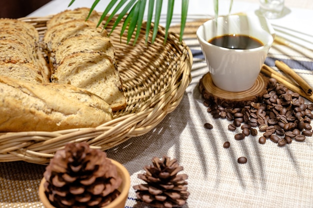 Tasse blanche de café avec des grains de café boulangerie et bâtons de cannelle sur une table en bois bleue