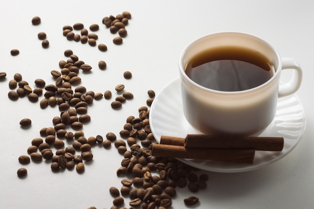 Tasse blanche avec café, grains de café sur une surface blanche