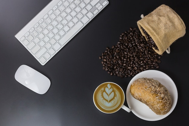 Tasse blanche de café et haricots sur fond noir