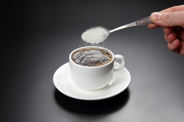 Tasse blanche avec café noir et cuillère à sucre