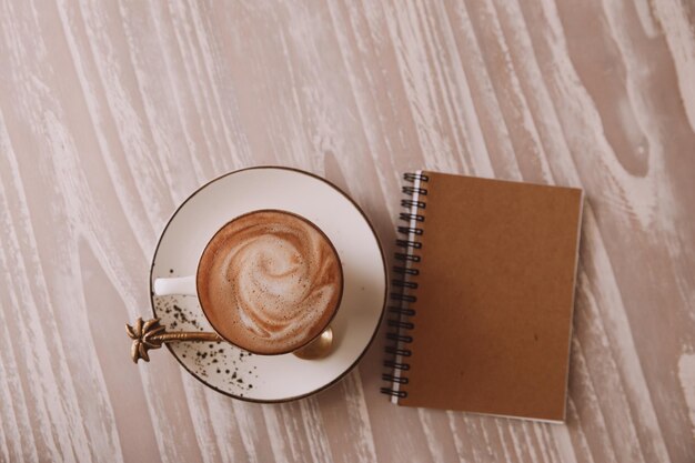 Tasse blanche de cappuccino chaud sur fond de table lumineuse en bois