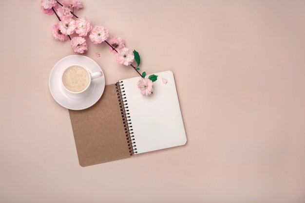 Tasse blanche avec cappuccino, fleurs de sakura, cahier rose