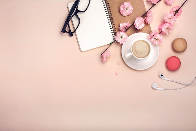 Tasse blanche avec cappuccino, fleurs de sakura, macarons, cahier