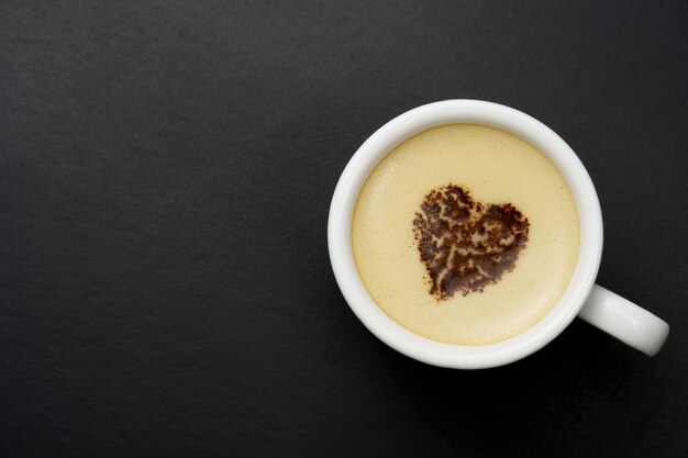 Tasse blanche de cappuccino, sur fond noir avec espace copie.