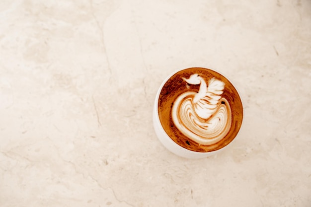 Tasse blanche de cappuccino savoureux avec art latte sur fond de marbre blanc au café