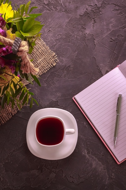 Tasse blanche avec un carnet et des fleurs