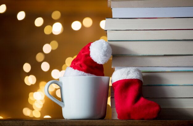 tasse blanche avec chapeau de Noël et des livres