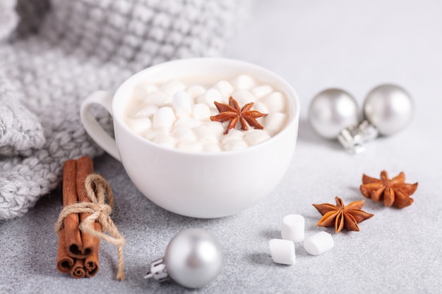 Tasse blanche avec chocolat chaud et guimauve, pull, cannelle