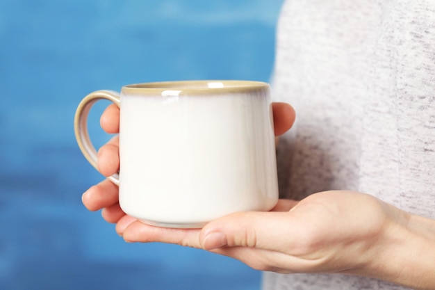 Une tasse blanche dans les mains en gros plan