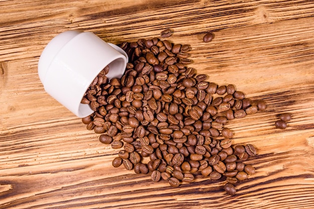 Tasse blanche et grains de café dispersés sur une table en bois Vue de dessus