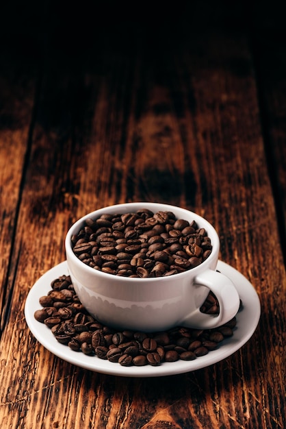 Tasse blanche pleine de grains de café torréfiés