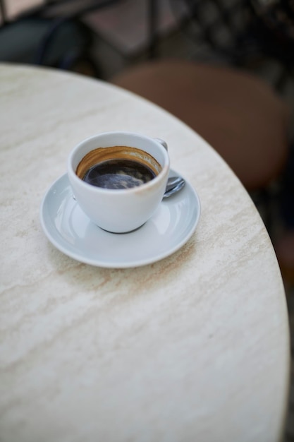 une tasse blanche et une soucoupe blanche avec du café se dressent sur la table en gros plan