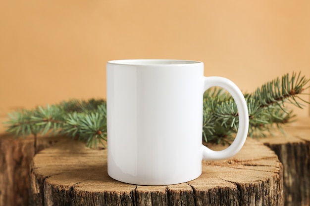 Tasse blanche sur un support en bois avec maquette de vue de face de branches de sapin pour l'espace de copie d'impression et la publicité