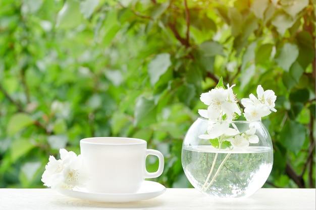 Tasse blanche de thé et un vase avec du jasmin.