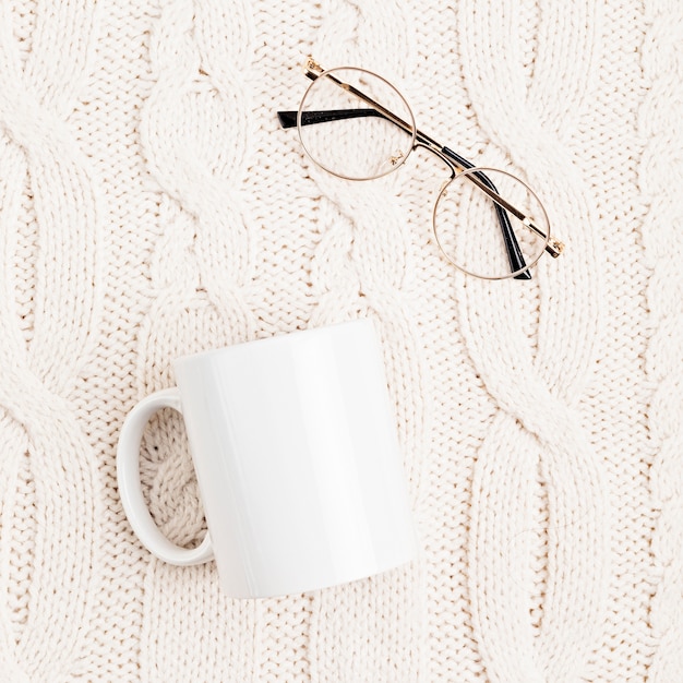 tasse blanche et verres sur une surface tricotée en laine blanche. Concept de lecture confortable. Mise à plat, vue de dessus
