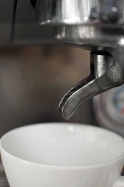 Tasse blanche vide dans la machine à café attend le café chaud fraîchement infusé