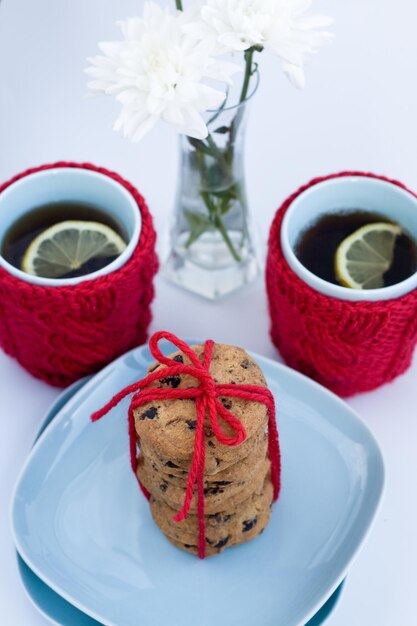 Tasse bleue avec couvercle en tricot rouge et biscuits au chocolat