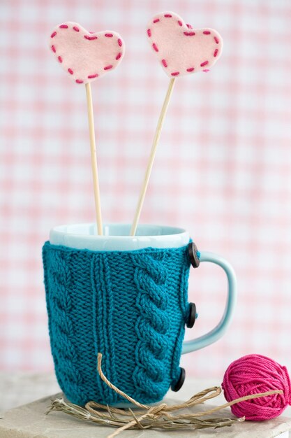 une tasse bleue dans un pull avec des coeurs