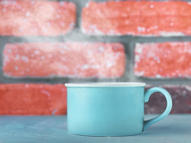 Photo tasse bleue avec du thé ou du café sur fond de mur de briques